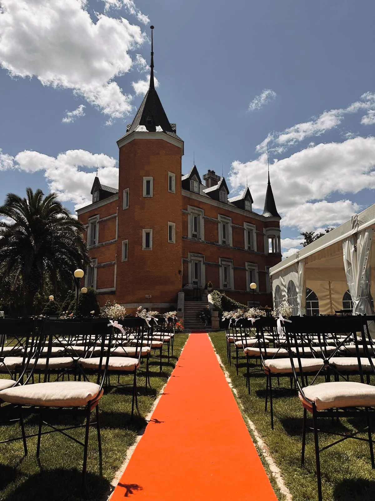 The aisle on the lawn of the Palacio de Silvela, leading to its steps, its red-brick front and its slate-spired turret